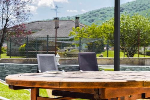 a wooden table and chairs with a view of a house at Can ventura alojamiento entero in La Vall de Bianya