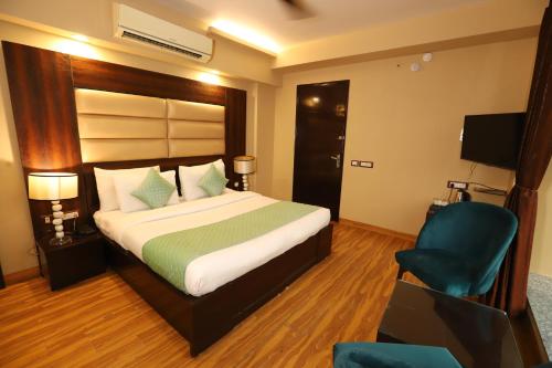 a bedroom with a large bed and a blue chair at Hotel Palm Grand Naraina New Delhi - Couple Friendly Local IDs Accepted in New Delhi