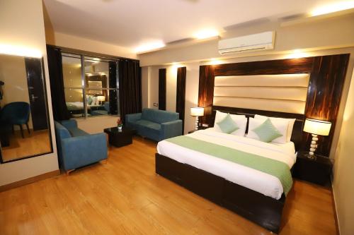 a bedroom with a large bed and two blue chairs at Hotel Palm Grand Naraina New Delhi - Couple Friendly Local IDs Accepted in New Delhi