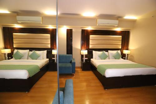 a hotel room with two beds and a mirror at Hotel Palm Grand Naraina New Delhi - Couple Friendly Local IDs Accepted in New Delhi