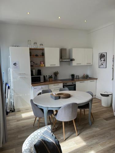 une cuisine avec une table et des chaises et une cuisine avec des armoires blanches dans l'établissement Magnifique Appartement 3 pièces Joliette Marseille PARKING PRIVATIF, à Marseille
