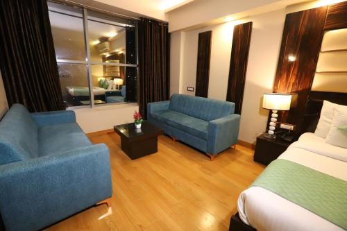 a hotel room with a bed and a couch and a chair at Hotel Palm Grand Naraina New Delhi - Couple Friendly Local IDs Accepted in New Delhi