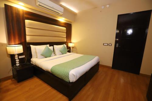 a bedroom with a large bed with two lamps at Hotel Palm Grand Naraina New Delhi - Couple Friendly Local IDs Accepted in New Delhi
