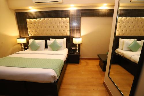 a hotel room with two beds and a mirror at Hotel Palm Grand Naraina New Delhi - Couple Friendly Local IDs Accepted in New Delhi
