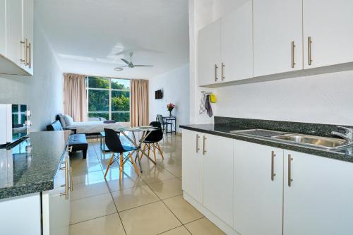 a kitchen and dining room with white cabinets and a table at Inn & Out Sandton Park in Johannesburg