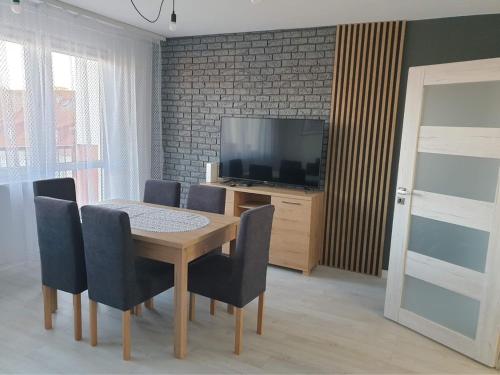 a dining room with a table and chairs and a television at Apartament Stanley in Iława