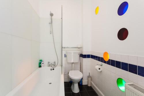 La salle de bains est pourvue de toilettes et d'une baignoire. dans l'établissement Large Shoreditch 2DBL bed loft apt, à Londres