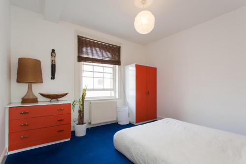 a bedroom with a bed and a dresser and a window at Large Shoreditch 2DBL bed loft apt in London