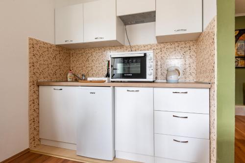 a kitchen with white cabinets and a microwave at Apartments and spa MIONA in Virpazar
