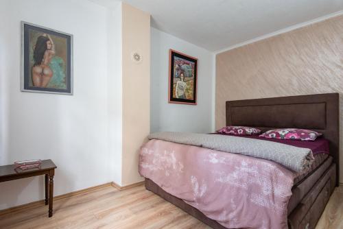 a bedroom with a bed with pink sheets and a table at Apartments and spa MIONA in Virpazar