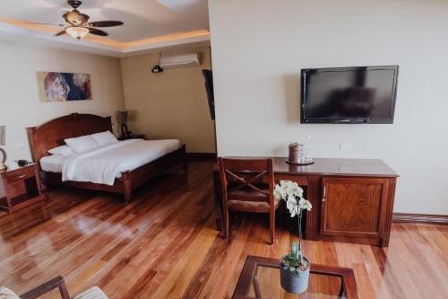 a bedroom with a bed and a tv on the wall at Hotel Dunn Inn in San José