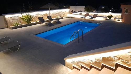 a swimming pool with chairs around it at night at Georgioupoli Studios in Georgioupolis