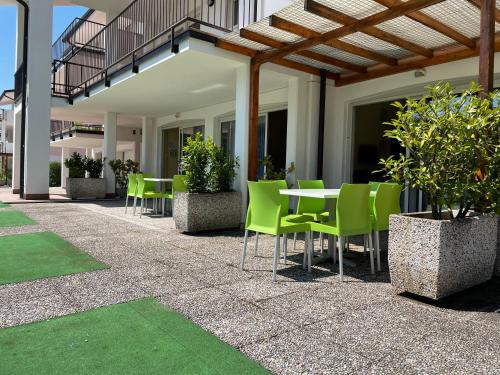 a patio with green chairs and a table at Bran & Denise Residence in Costermano sul Garda