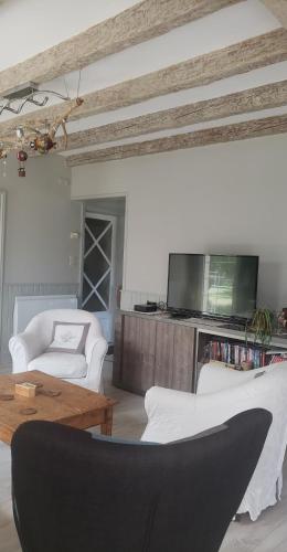 a living room with two white couches and a tv at Chambre Zen à la campagne in Marennes