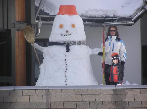 a woman and a child standing next to a snowman at Hotel Tripič, restaurant and pizzeria in Bohinj