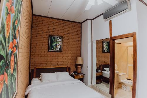 a bedroom with a bed and a brick wall at Hotel Dunn Inn in San José