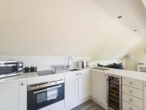 a white kitchen with a sink and a microwave at Stunning home with hot tub in picturesque village in Haddenham