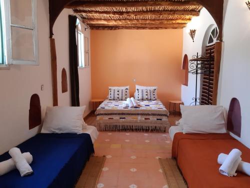 a room with two beds and two windows at Riad Douar Des Oliviers in El Arba