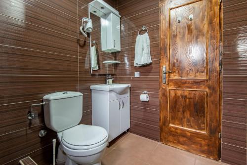 a bathroom with a toilet and a wooden wall at Apartments and spa MIONA in Virpazar