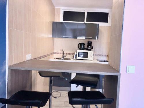 małą kuchnię z blatem ze stołkami i kuchenką mikrofalową w obiekcie Estudio Benalmádena Costa w mieście Benalmádena