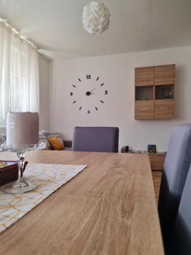 a dining room table with a clock on the wall at Apartment Pemper - Self check in and check out in Otočac