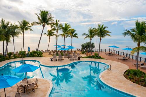 - une piscine avec des chaises, des parasols et des palmiers dans l'établissement Postcard Inn Beach Resort & Marina, à Islamorada
