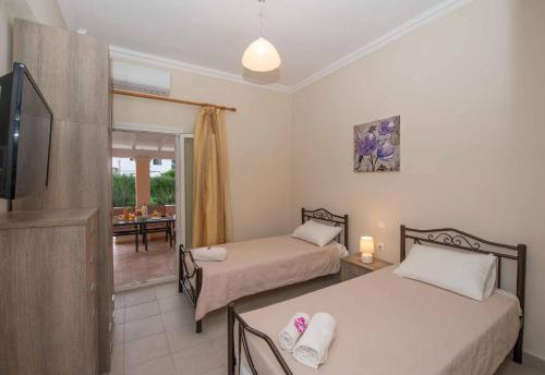 Pokój z 2 łóżkami, telewizorem i jadalnią w obiekcie Lollas Apartments Acharavi Corfu w Acharavi