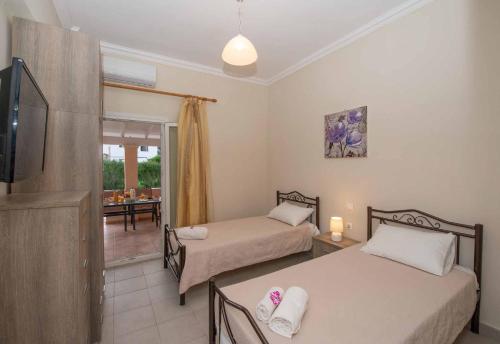 une chambre avec deux lits, une télévision et une salle à manger dans l'établissement Lollas Apartments Acharavi Corfu, à Acharavi