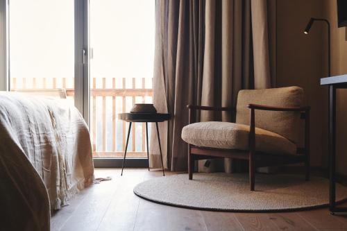 a bedroom with a chair and a window at Boutiquehotel DAS ZEITWERT in Deutschlandsberg