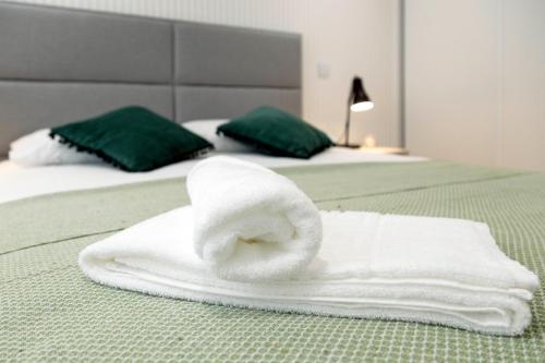 een stapel witte handdoeken op een bed bij Delmar I in Nazaré