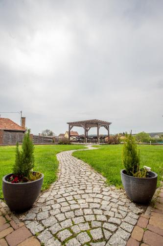 a stone walkway with a gazebo in a park at Petrény Borpanzió in Egerszalók