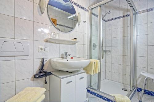 ein weißes Bad mit einem Waschbecken und einer Dusche in der Unterkunft Gästehaus Lärcheck Berchtesgaden FeWo Wiesentraum in Berchtesgaden
