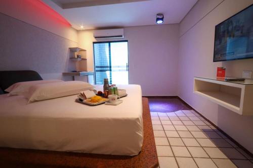 a bedroom with a bed with a tray of food on it at Eros Hotel CDU (Adults Only) in Recife