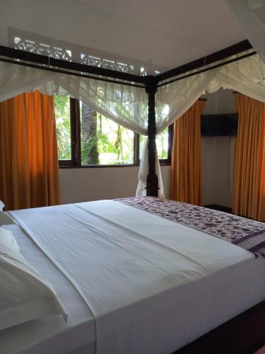 a bedroom with a large white bed with a canopy at Bali North Beach Villa - Ocean Front in Tianyar