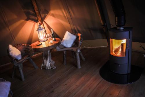 a room with a wood stove and a table and chairs at Scaldersitch Farm Boutique Glamping Tipi with private wood fired hot tub in Sheen