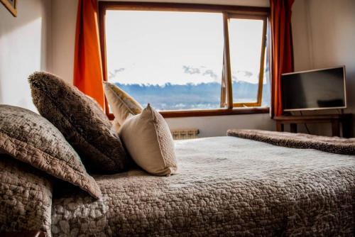 a bedroom with a bed with pillows and a window at OIKOS in Ushuaia