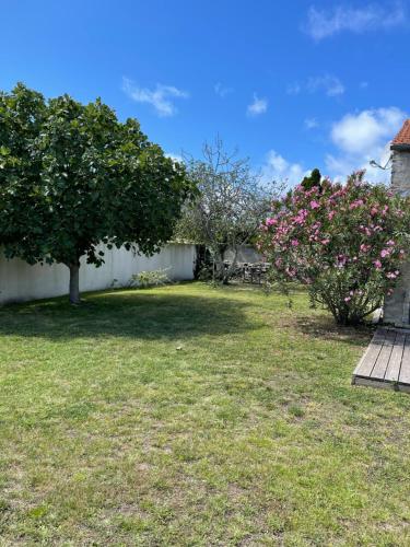 une cour avec deux arbres et des fleurs roses dans l'établissement Les Figuiers N°2 - Repos et tranquillité, à La Michelière