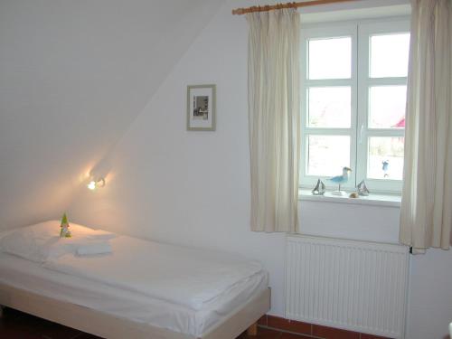 a white bedroom with a bed and a window at Ferienparadies Rugana C07 in Kreptitz
