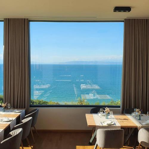 a dining room with tables and chairs and a large window at Duplex Seaview Condo in Durrës