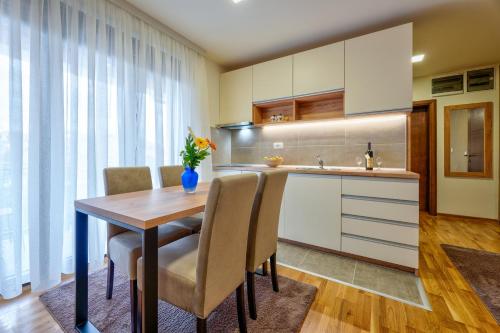 a kitchen with a wooden table with chairs and a counter at Monix Palace Zlatibor in Zlatibor