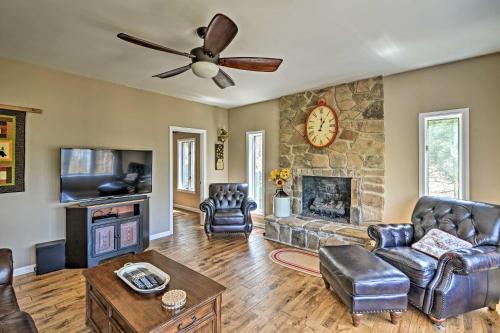 a living room with a stone fireplace and a ceiling fan at Family-Friendly Terra Alta Home with Lake View! in Terra Alta