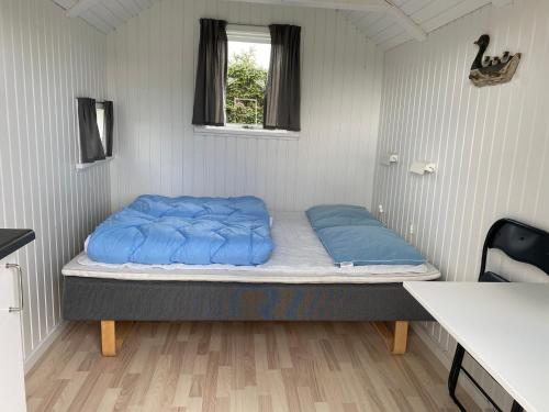 ein Zimmer mit einem Bett mit blauen Kissen darauf in der Unterkunft Asaa Camping & Cottages in Aså