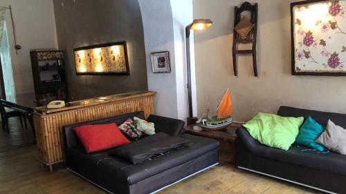 a living room with two black couches with colorful pillows at Americo Pousada e Hostel in São Luís