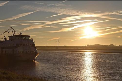 a ferry boat in the water at sunset at Landschaftliches Haus in Tönning