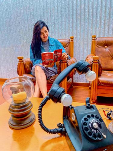 a woman sitting in a chair reading a book next to a telephone at Hotel Maceo Chico in Bogotá