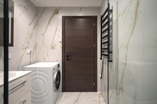 a bathroom with a washing machine and a glass door at Kaunas City Center Deluxe in Kaunas