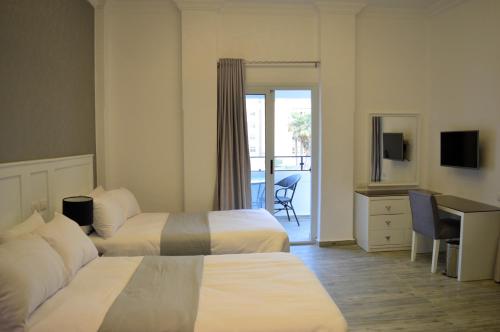 um quarto de hotel com duas camas e uma secretária em Nile Villa Hotel no Cairo