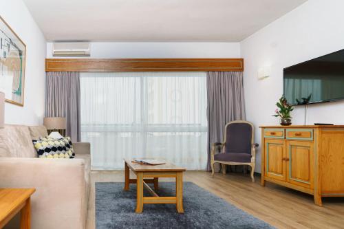 a living room with a couch and a tv at Luna Hotel da Oura in Albufeira