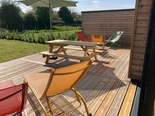 une terrasse en bois avec une table de pique-nique et des chaises dans l'établissement Songes en Côte d Opale, à Conteville-lès-Boulogne