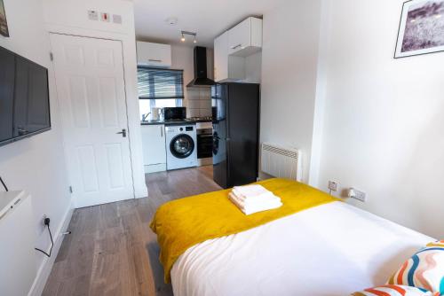 um quarto com uma cama com um cobertor amarelo em No 01 Small Studio flat in Aylesbury town Station em Buckinghamshire